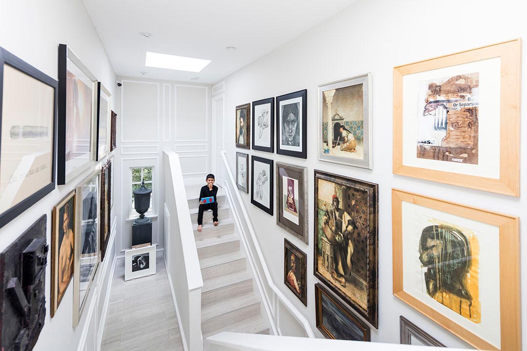 Ean, Yücel'in fotoğraftan resime sanat koleksiyonundan parçaların çevrelediği ahşap merdivenlerde (eyinteriors.com)